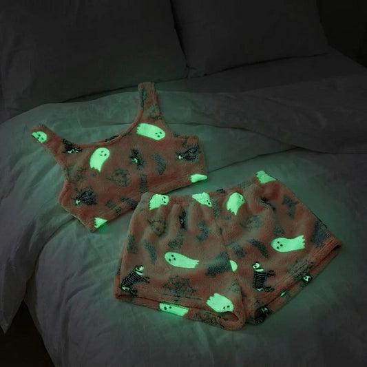 Coral peach fleece Halloween pajama set glowing green on a bed